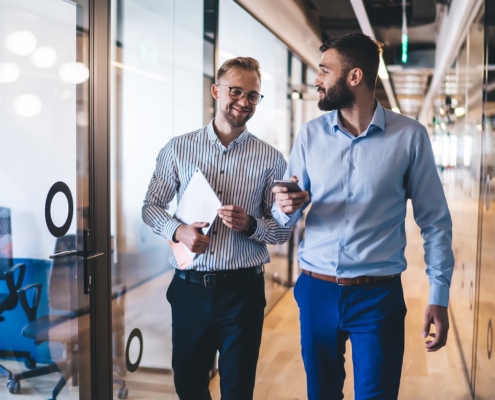 Two people walking in office with laptop