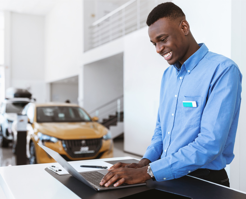 Car salesman at dealership looking at laptop